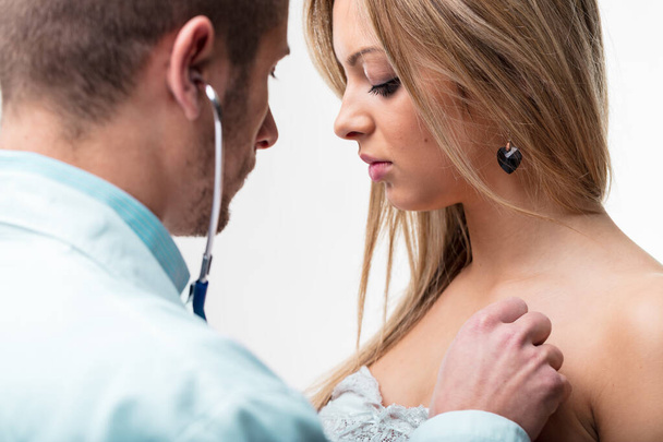 Young woman participates in a routine health examination, with the doctor's stethoscope indicating a cardiac assessment - Photo, Image