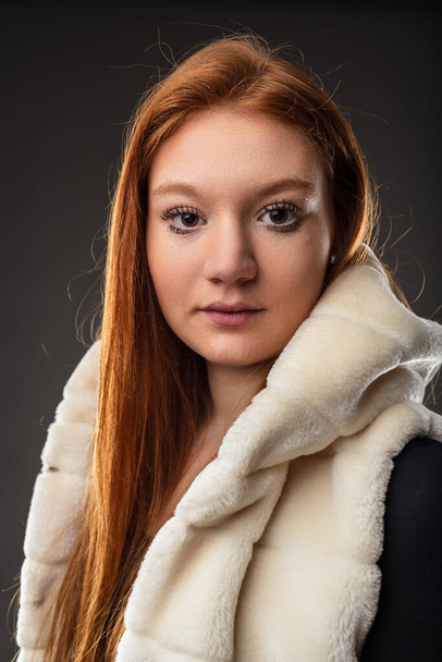 Red-haired woman stands out in a faux fur coat, her gaze intense - Photo, Image