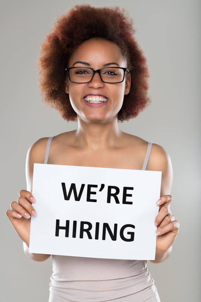 Enthusiastic woman holds a 'We're Hiring' sign, her bright smile inviting potential applicants - Photo, Image
