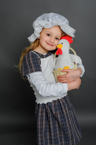 Girl in dress rustic vintage holds a chicken in a basket - Photo, Image