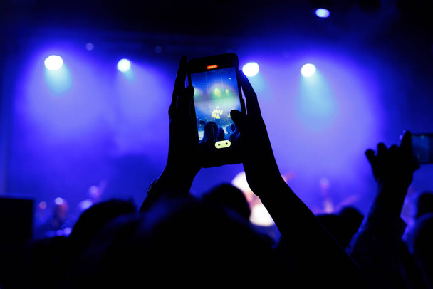 Silhouette di una folla a un concerto dal vivo, braccia alzate, scattare selfie - Foto, immagini