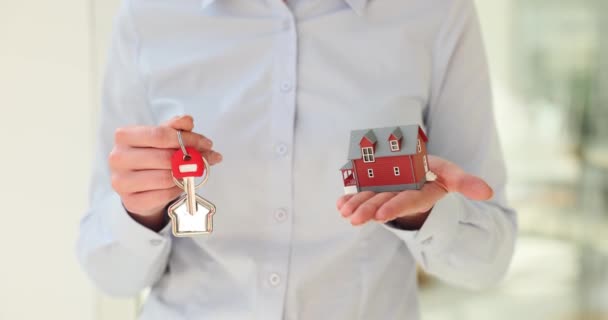 Žena realitní makléř nabízí městský dům možnosti pro klienta držící v ruce malý model dvoupodlažní budovy a klíč. Agentura nabízející nákup a pronájem nemovitostí - Záběry, video
