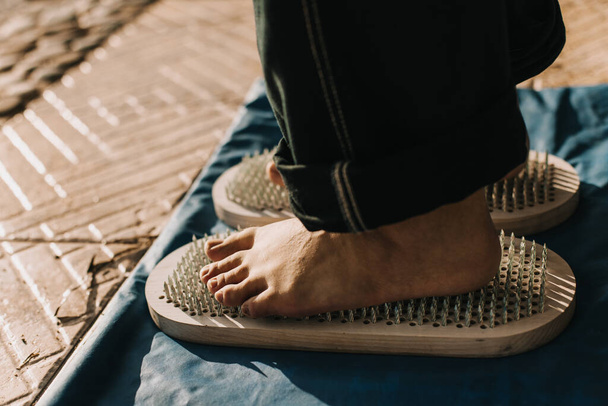 Pies de pie sobre una tabla de Sadhu (Yoga board) con clavos afilados al aire libre. Practica yoga, meditación, concentración. Primer plano. - Foto, Imagen