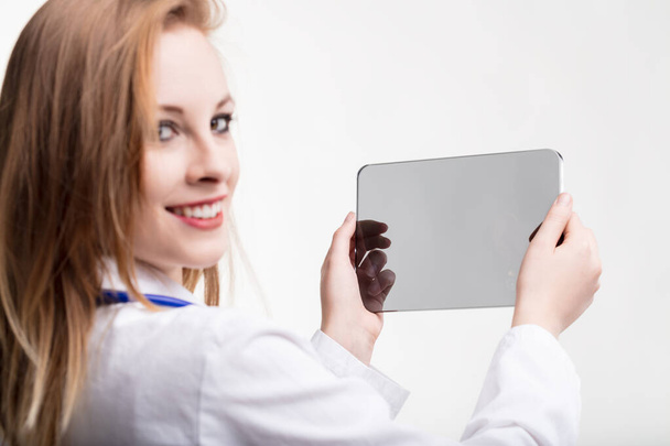Mediziner strahlen, während sie eine futuristische transparente Tablette in der Hand halten, die innovative Gesundheitstechnologie symbolisiert - Foto, Bild