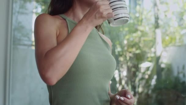 Наклоните медленно веселую кавказскую женщину, пьющую кофе из кружки на завтрак, проводя выходные дома - Кадры, видео