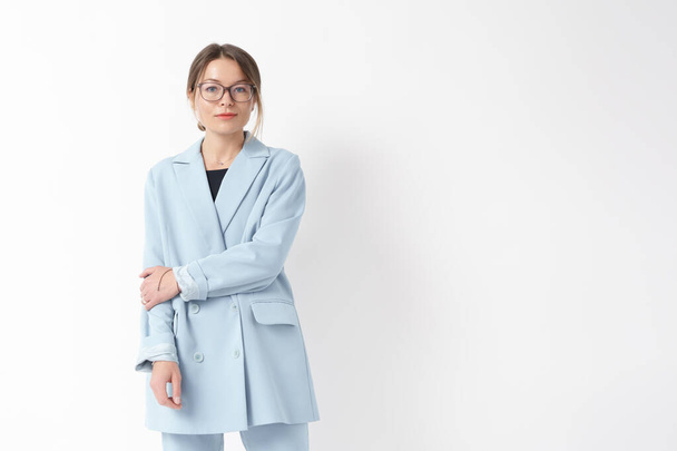Elegant gekleidete Geschäftsfrau in pastellblauem Blazer und Brille, die einen smarten und modernen Look präsentiert - Foto, Bild