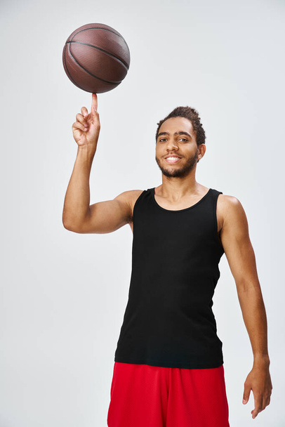 aantrekkelijke vreugdevolle Afrikaan amerikaanse man in sportwear houden basketbal en kijken naar camera - Foto, afbeelding