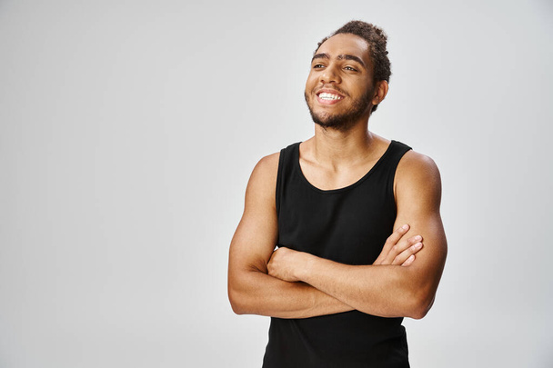allegro bell'uomo africano americano in abbigliamento sportivo in posa con le braccia incrociate su sfondo grigio - Foto, immagini