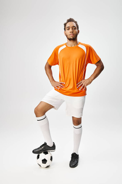 bonito afro-americano homem em sportwear com futebol com braços akimbo e olhando para a câmera - Foto, Imagem