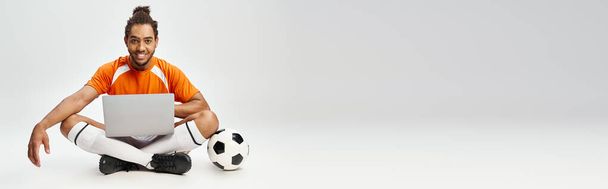 εύθυμος Αφροαμερικάνος με ποδόσφαιρο και laptop κοιτάζοντας κάμερα, online στοιχήματα, banner - Φωτογραφία, εικόνα