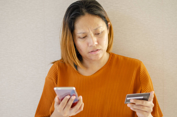 Stresowana kobieta, scammer kradzież pieniędzy z transakcji online, trzymając kartę kredytową i telefon komórkowy, Izolacja tle - Zdjęcie, obraz