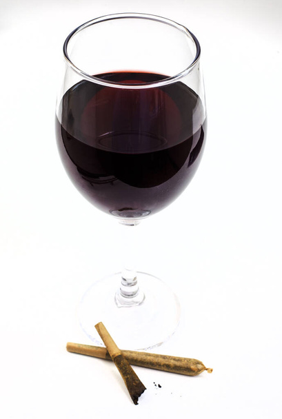 Articulación de marihuana y copa de vino tinto sobre blanco  - Foto, imagen