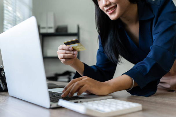 Mujer joven hace una compra en Internet en el portátil con tarjeta de crédito. - Foto, Imagen