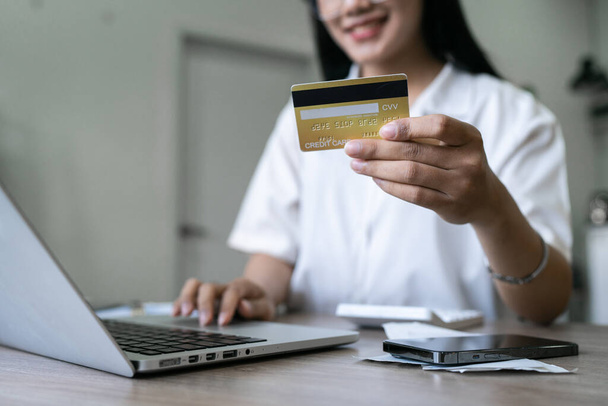 Jeune femme fait un achat sur Internet sur l'ordinateur portable avec carte de crédit. - Photo, image