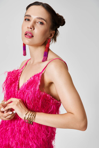 グレーの背景に対して胸に触れるファッショナブルなピンクの服に自信を持った女性 - 写真・画像