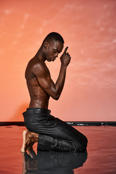 appealing african american man in black wet pants sitting on water surrounded by vivid lights - Photo, Image