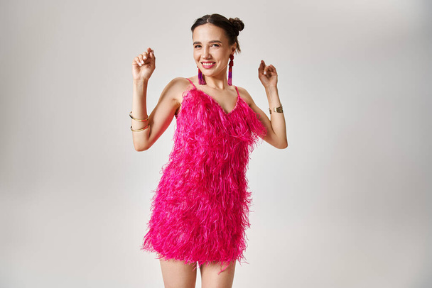 Izgalmas fiatal barna lány divatos rózsaszín ruha gerendák, tánc szürke háttér - Fotó, kép