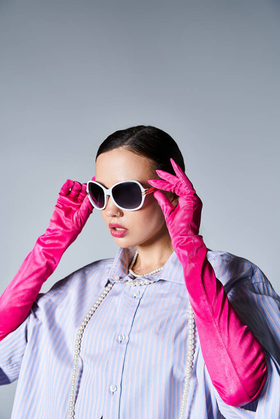 Pretty brunette woman in violet shirt and leather gloves touches her stylish sunglasses - Photo, Image