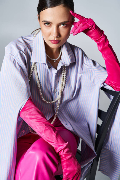Donna bruna che indossa guanti rosa e vestito alla moda, toccandosi la fronte - Foto, immagini