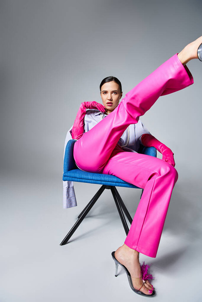 Confident brunette woman in trendy pink pants and shoes, sitting and kicking her leg up - Photo, Image