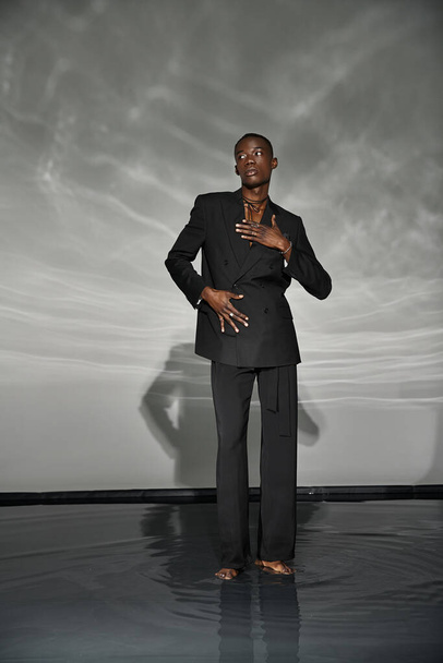 vonzó elegáns afro-amerikai férfi szexi kigombolt öltöny pózol szürke vizes háttér - Fotó, kép