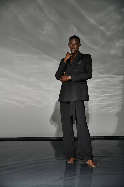 engageant l'homme afro-américain en costume noir déboutonné posant allègrement et regardant la caméra - Photo, image