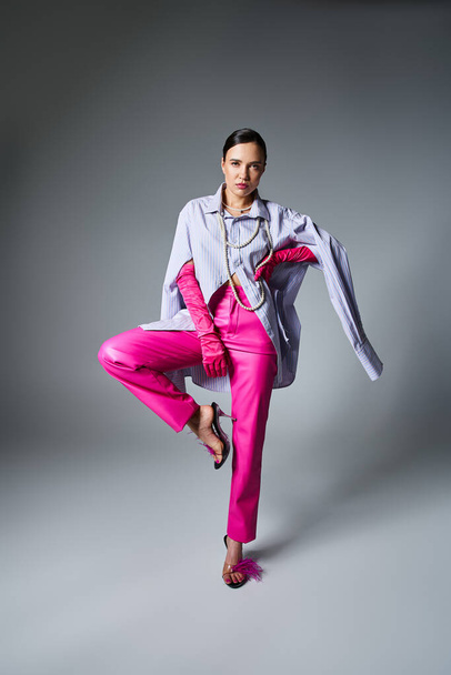 Morena de moda con guantes rosas y pantalones de cuero de pie en pose de moda aislada - Foto, imagen