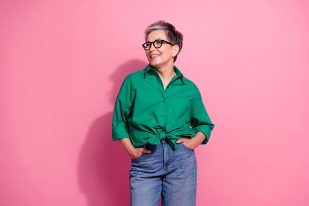 Photo portrait of attractive pensioner woman look empty space shopping wear trendy green clothes isolated on pink color background. - 写真・画像