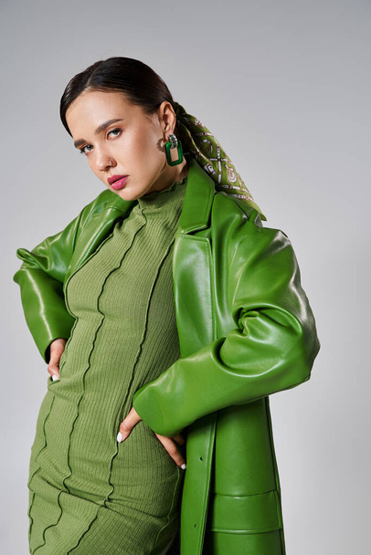 Μοντέρνα γυναίκα στο σύνολο πράσινο μοντέρνα εμφάνιση σε γκρι φόντο ποζάρουν με τα χέρια στη μέση - Φωτογραφία, εικόνα