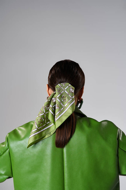 スタジオ設定でグリーンレザージャケットとヘッドスカーフを着用したブルネット女性のバックビュー - 写真・画像