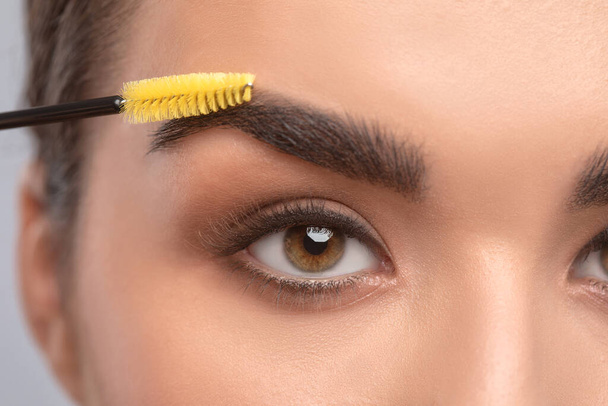 Maquillaje artista peina las cejas con un cepillo después de teñir en un salón de belleza.. - Foto, imagen