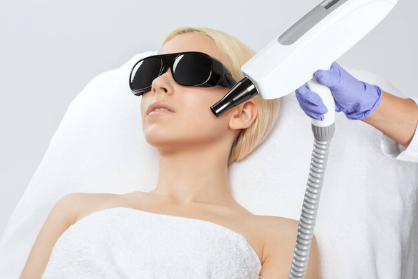 Esteticista faz remoção de tatuagem a laser para uma mulher bonita em suas sobrancelhas. Tratamento de cosmetologia de hardware no salão de beleza. - Foto, Imagem