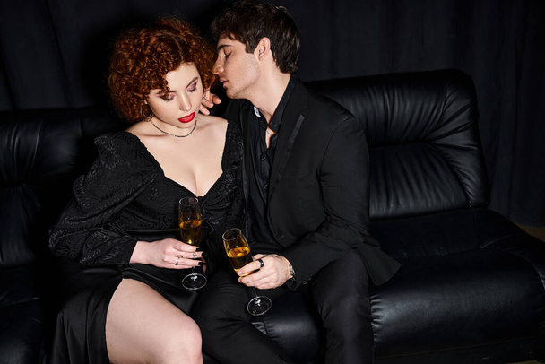 привлекательная девушка и парень проводит время на диване с бокалами шампанского, сексуальная пара - Фото, изображение