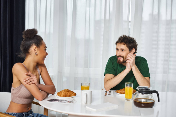 atrakcyjne piękne międzyrasowe para w casual stroje korzystających ich pyszne śniadanie w domu - Zdjęcie, obraz