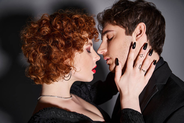 kusząca seksowna para w czarnych eleganckich ubraniach przygotowujących się do pocałunku na szarym tle - Zdjęcie, obraz
