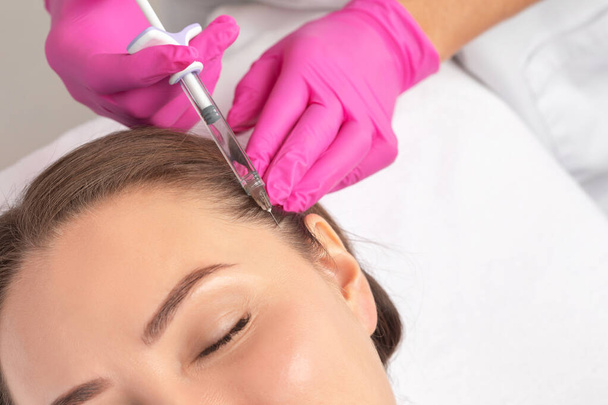 Косметолог проводить ін'єкційну терапію проти випадіння волосся і протиотрути красивої жінки в салоні краси. концепція косметології. - Фото, зображення