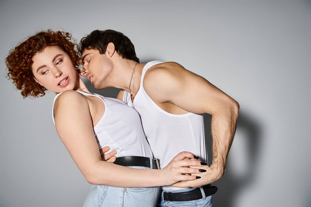atractivo sexy pareja en casual acogedor atuendos abrazándose calurosamente antes de besar en gris telón de fondo - Foto, imagen
