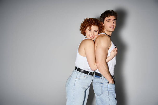 alegre atractivo pareja en acogedor azul jeans abrazando calurosamente y sonriendo a la cámara, sexy pareja - Foto, Imagen