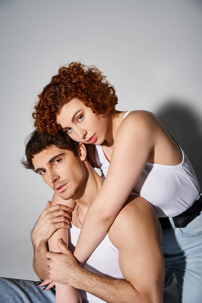 привлекательный мужчина и женщина в повседневной одежде сидят на полу и обнимаются с любовью, сексуальная пара - Фото, изображение