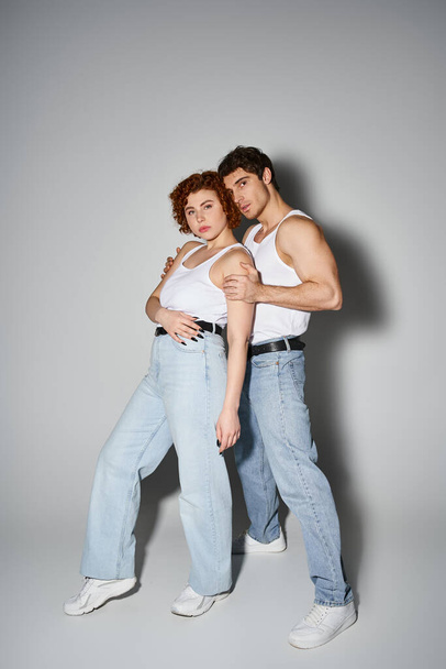 σαγηνευτικό άντρας και γυναίκα σε casual blue jeans αγκαλιάζει θερμά και κοιτάζοντας την κάμερα, σέξι ζευγάρι - Φωτογραφία, εικόνα