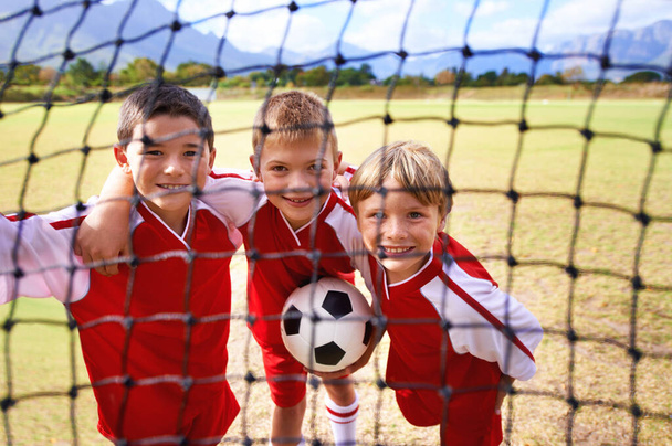 ゴールネット上の少年,サッカー選手,ボール,笑顔,ゲーム,フィールド,子供のために幸せ. 子供の頃のための屋外,遊び,スポーツ,試合のための肖像画およびスポーツ,サッカーのピッチの外. - 写真・画像
