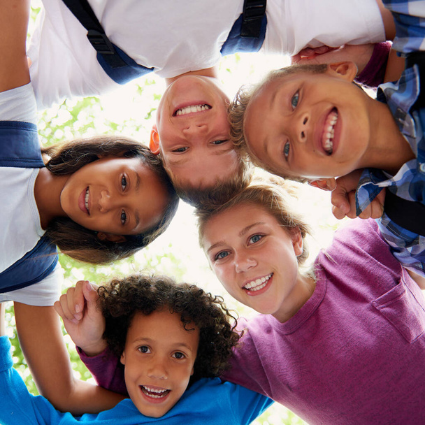 子供,女性,ハドル 幸せな肖像画で,遊び場の屋外の木および日光. 学校のフィールド,夏,または都市の教育支援との連帯に関する学生,教師または多様性. - 写真・画像