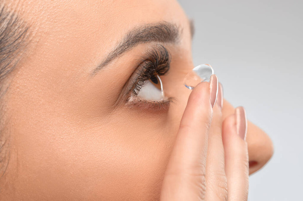 Una donna tiene la lente a contatto al dito. La cura degli occhi e la scelta tra i mezzi per migliorare la visione. - Foto, immagini