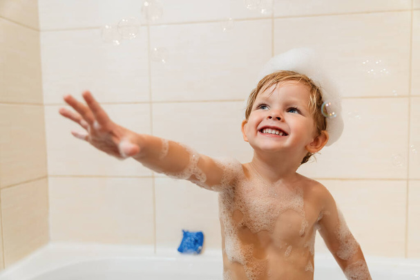 Roztomilý malý chlapec se baví ve vaně s pěnou a bublinkami. - Fotografie, Obrázek
