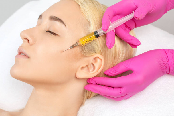 Kosmetikerin macht Prp-Therapie auf dem Gesicht einer schönen Frau in einem Schönheitssalon. Kosmetologie-Konzept. - Foto, Bild