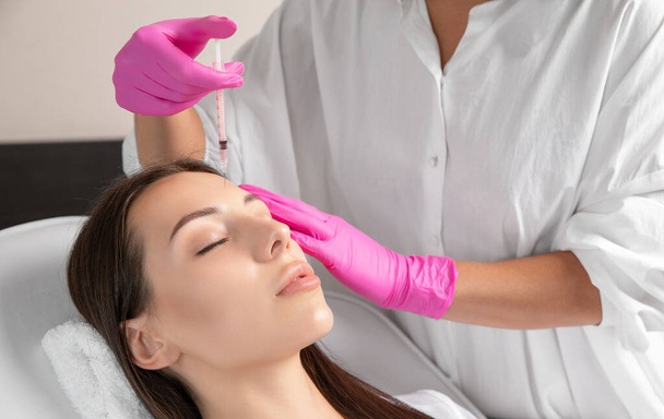 El cosmetólogo hace rejuvenecedoras inyecciones antiarrugas en la cara de una mujer hermosa. Cosmetología estética femenina en un salón de belleza. - Foto, Imagen