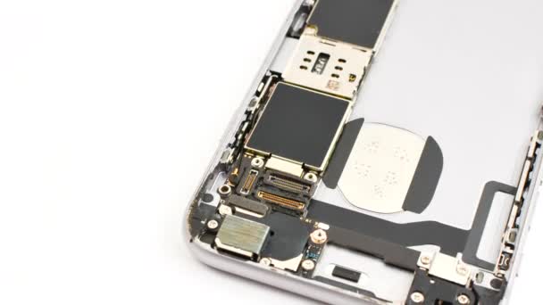 Close-up of a smartphone in repair on a white background, showcasing its internal components. Smartphone taken apart for maintenance on a light surface, displaying its engineering. - Footage, Video