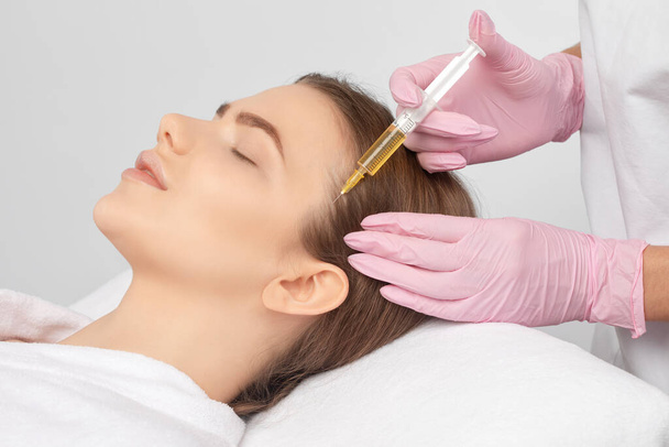 Cosmetoloog doet prp therapie tegen haaruitval en anti-roos van een mooie vrouw in een schoonheidssalon. Esthetische kosmetologie concept, haarbehandeling. - Foto, afbeelding