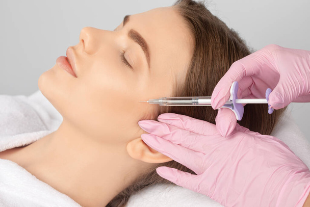 Cosmetologist faz injeções rejuvenescedoras anti rugas no rosto de uma mulher bonita. Cosmetologia estética feminina em um salão de beleza. - Foto, Imagem
