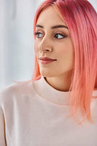 привлекательная радостная женщина с розовыми яркими волосами в случайном белом свитере позирует и смотрит в сторону - Фото, изображение